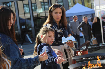 A girl and her mother toast a marshmallow.