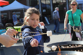 A girl and her mother toast a marshmallow.